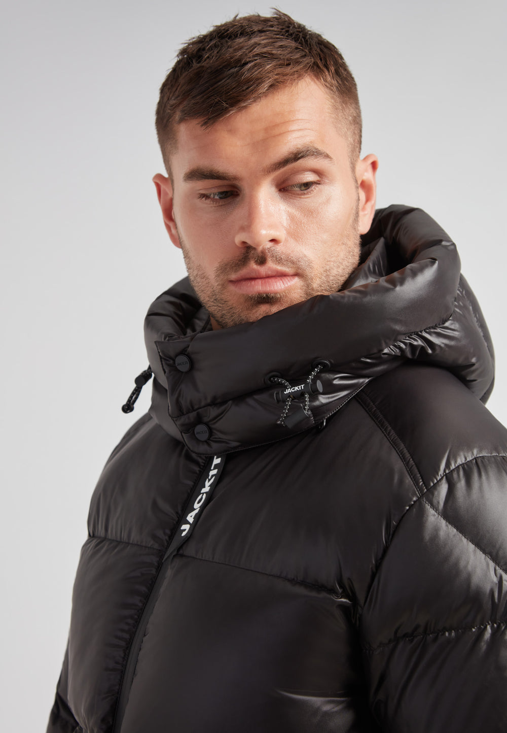 Close-up of a man wearing the EZ Water Puffer Racer Jacket Lux Black with a stylish padded hood.