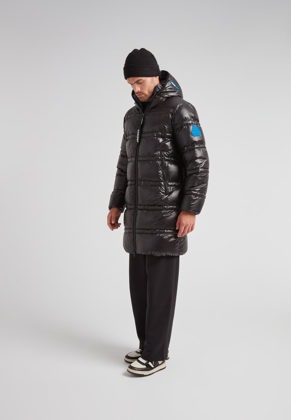 R4D Tramline Puffer Coat Lux Black worn by a man standing in profile, showcasing its longline design and insulation.