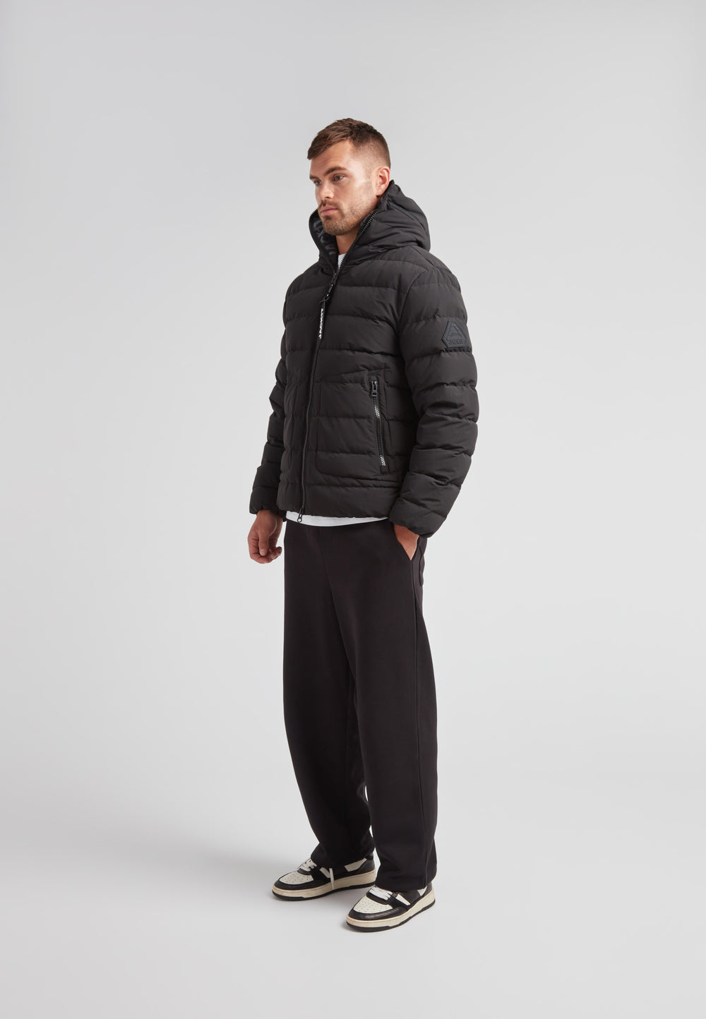 R4D Tramline Puffer Racer Jacket Matt Black worn by man standing, showcasing modern style and warmth.