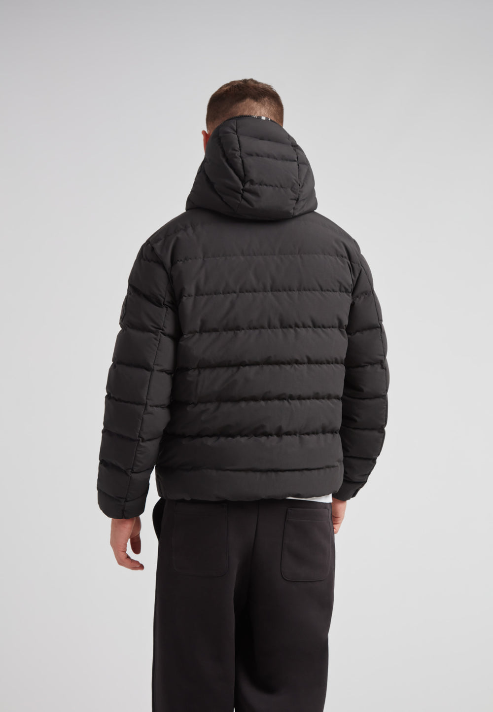 Back view of R4D Tramline Puffer Racer Jacket Matt Black showcasing its puffer design and hood.