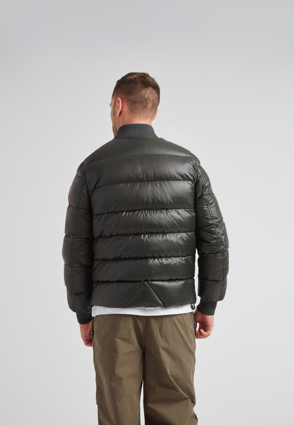 Back view of a man wearing the Vortex olive bomber jacket in a modern design with a matte finish.