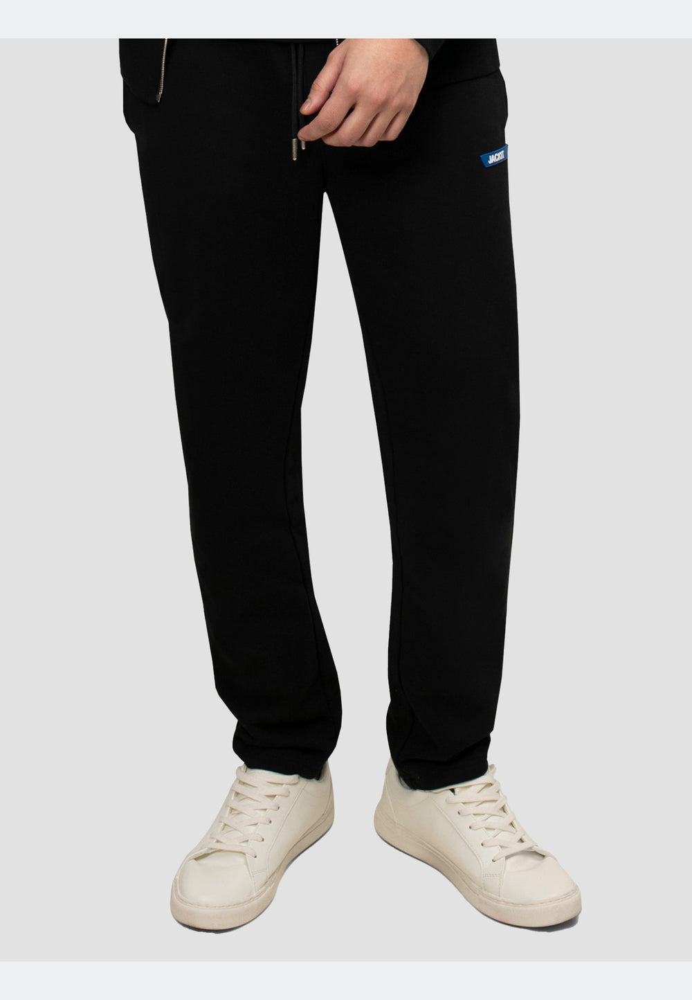 Model wearing black joggers with an elasticated waistband and side pockets, paired with white sneakers.
