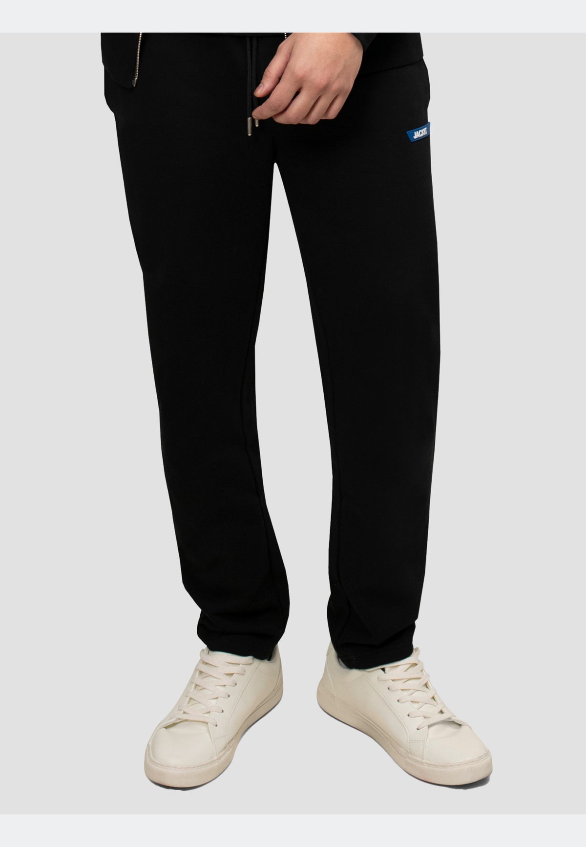 Model wearing black joggers with an elasticated waistband and side pockets, paired with white sneakers.