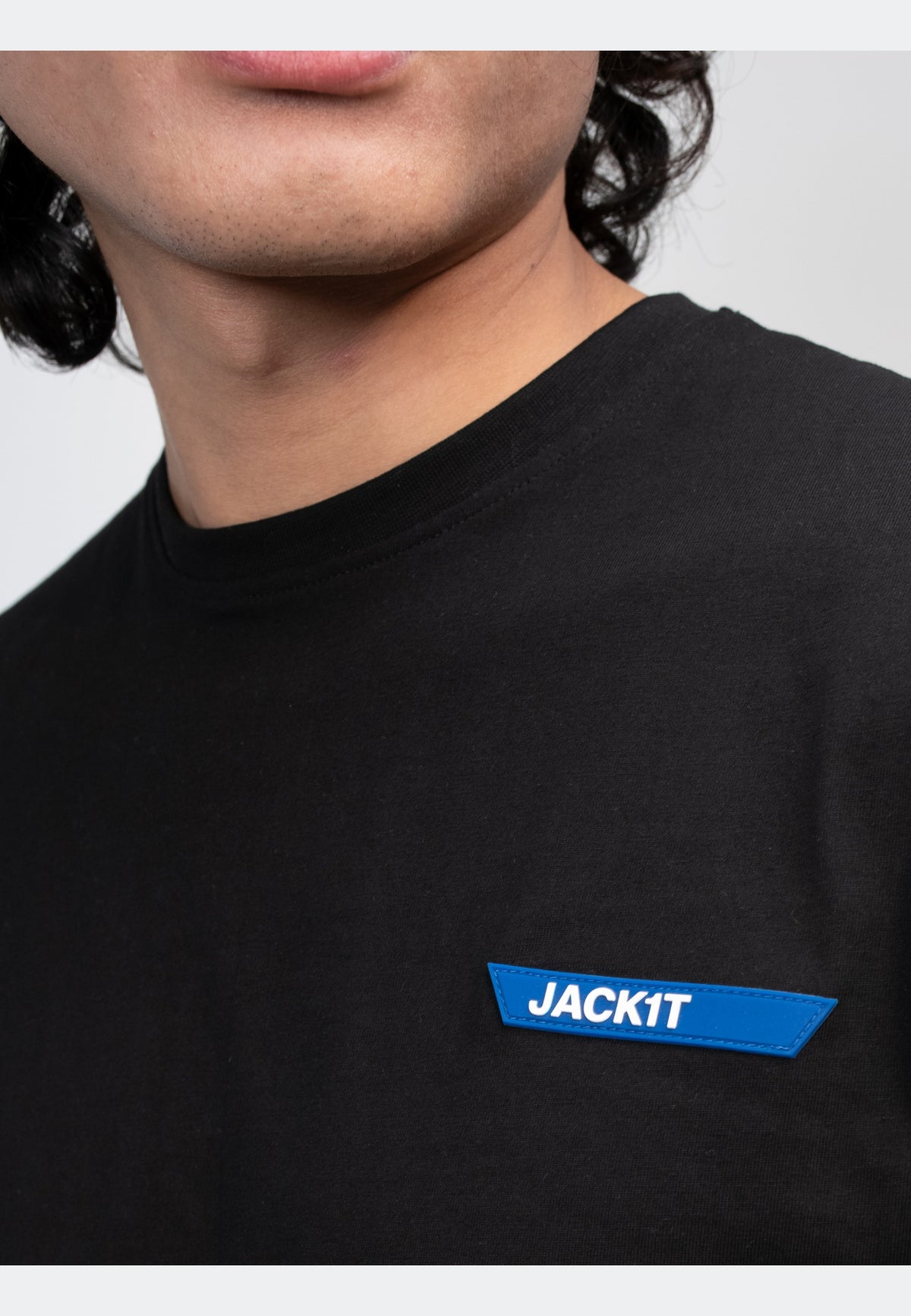 Close-up of a man wearing a black t-shirt with a blue JACKIT logo on the chest.
