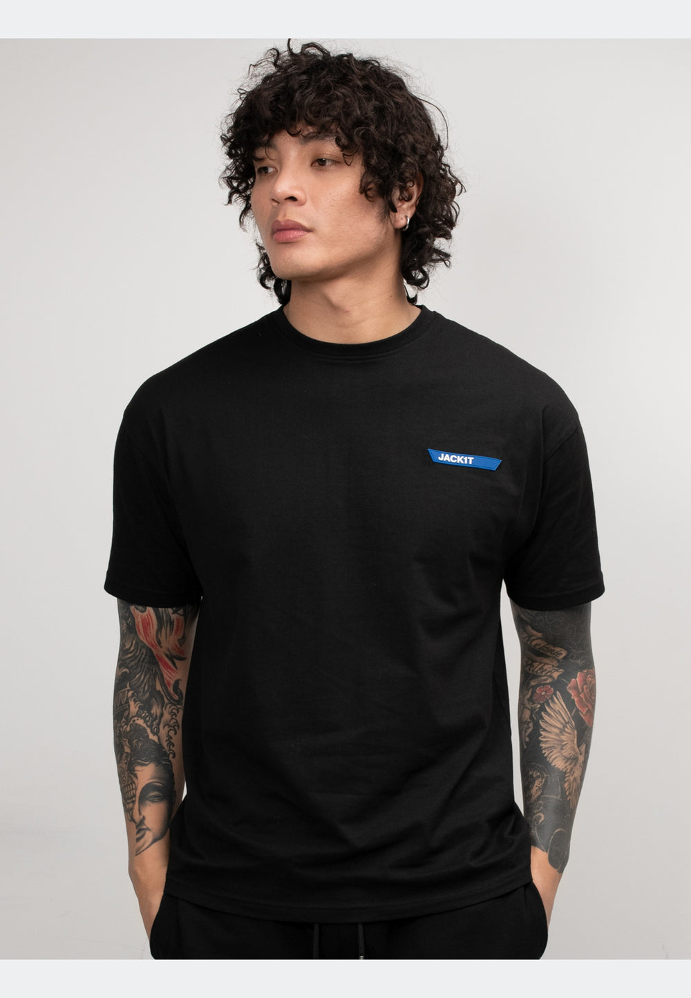 Black t-shirt on a model with tattoos, showcasing a stylish design and comfortable fit.