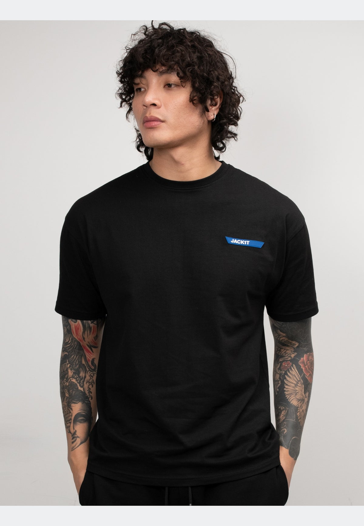 Black t-shirt on a model with tattoos, showcasing a stylish design and comfortable fit.