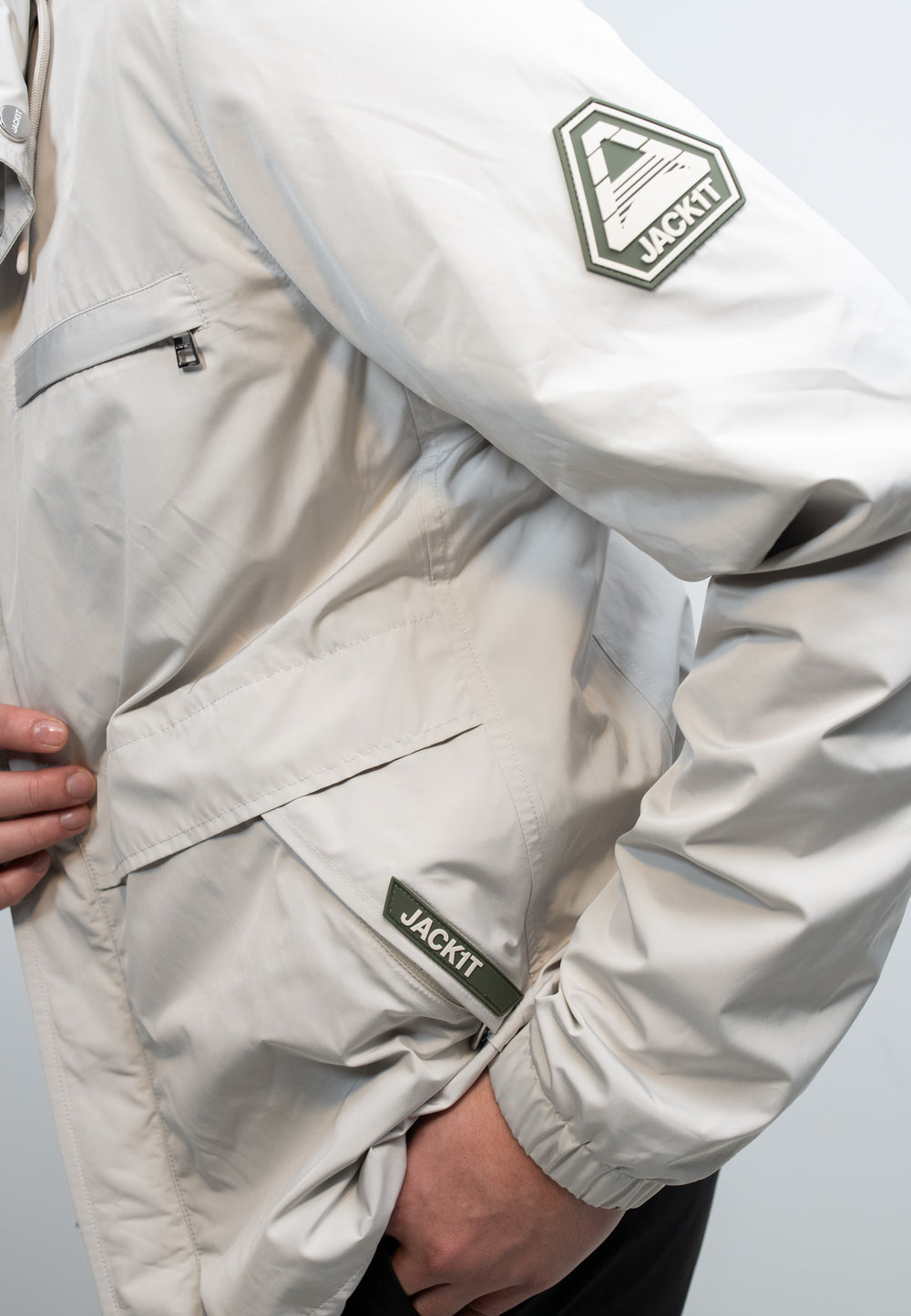 Men's stone windbreaker in lightweight stone color with functional pockets and branding details.