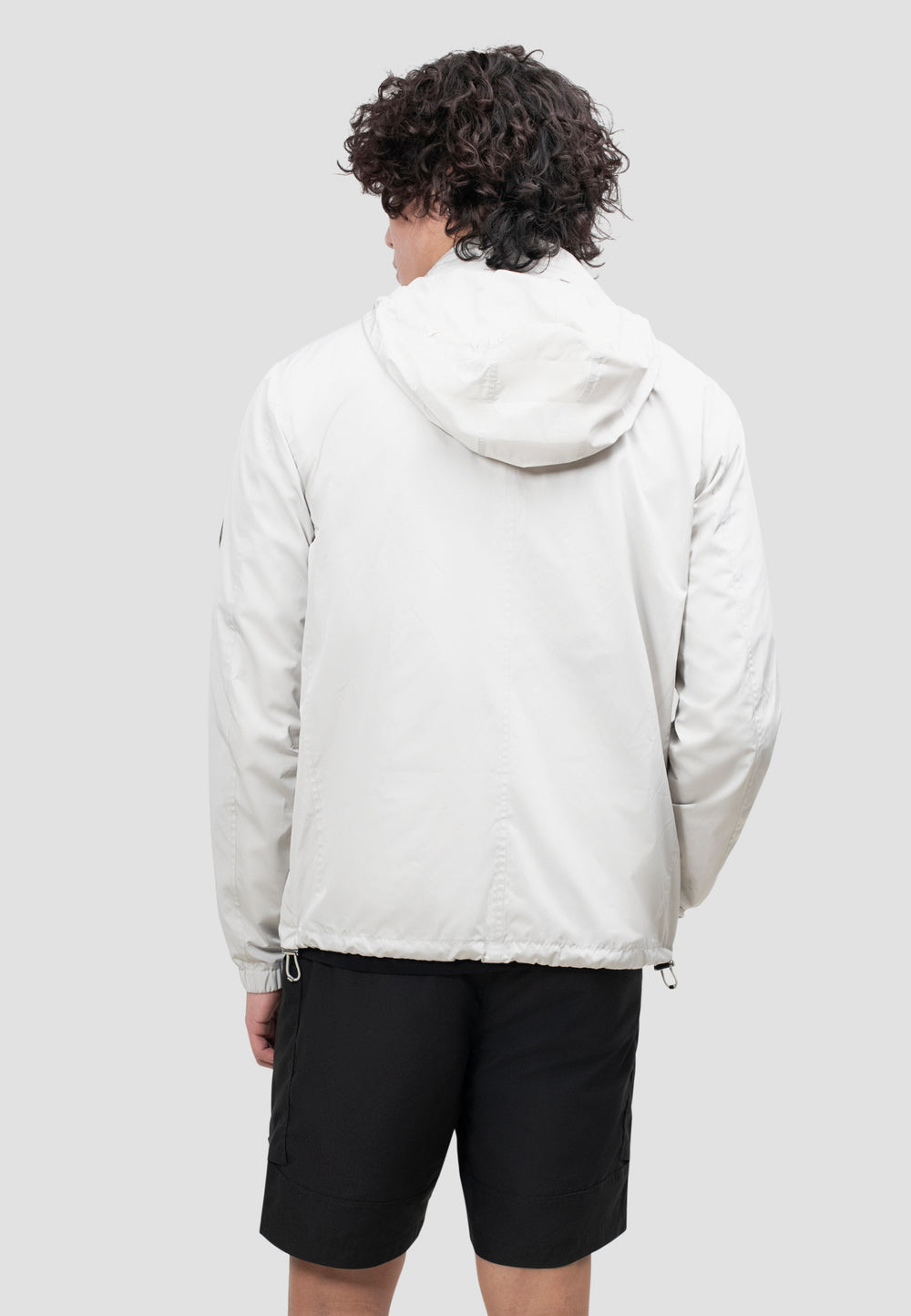 Back view of a man wearing a lightweight men's stone windbreaker in stone color, ideal for spring and summer weather.