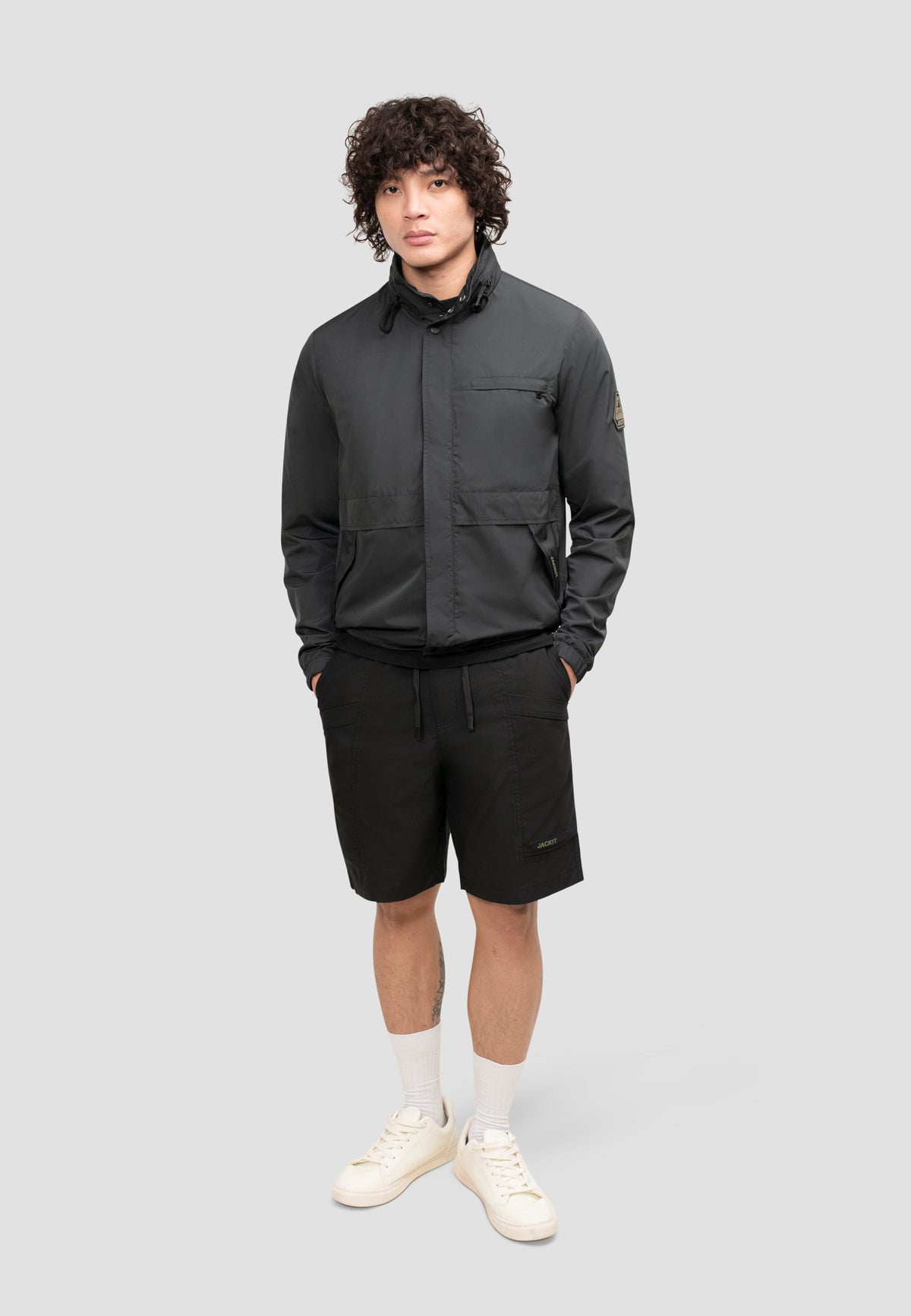 Men's black windbreaker model wearing it with shorts, showcasing breathability and style for spring weather.