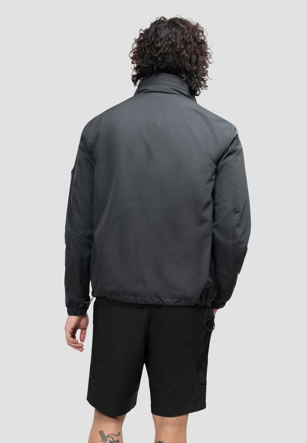 Back view of a model wearing a men's black windbreaker, showcasing its lightweight and functional design.