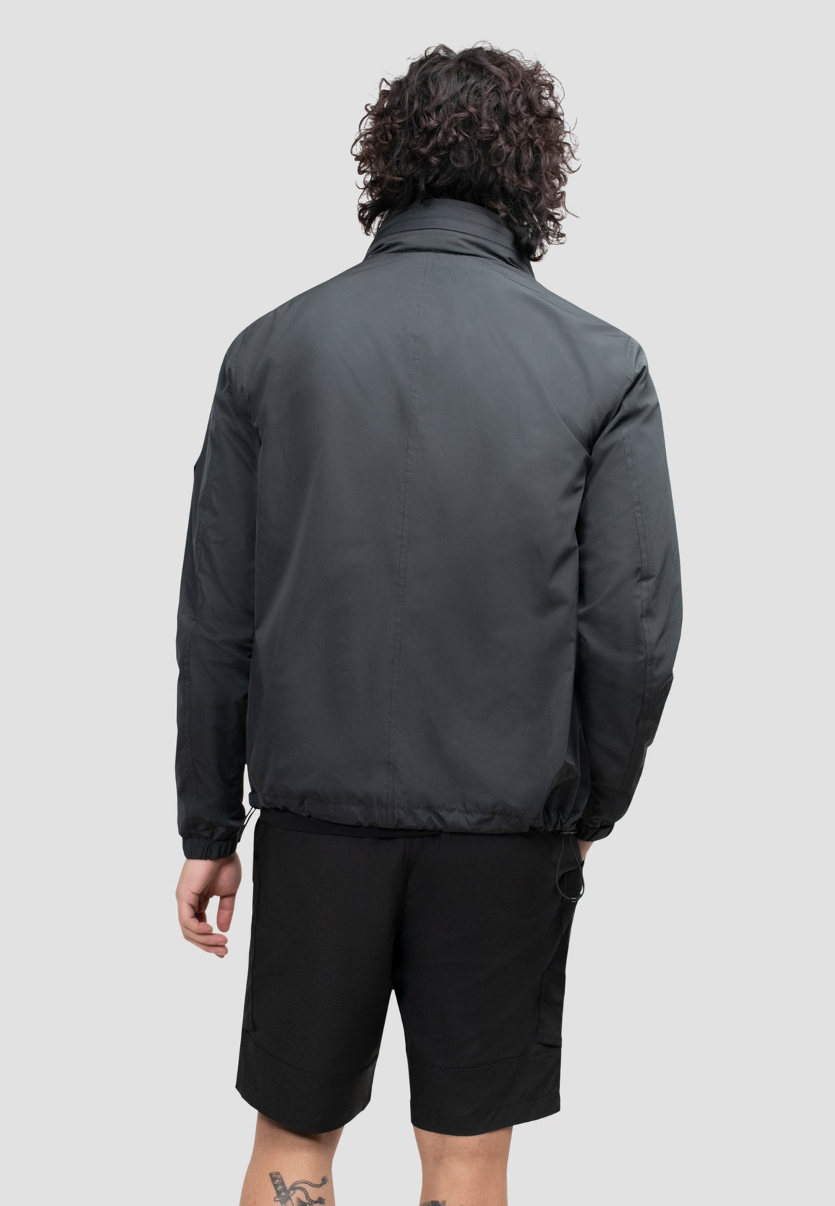 Back view of a model wearing a men's black windbreaker, showcasing its lightweight and functional design.