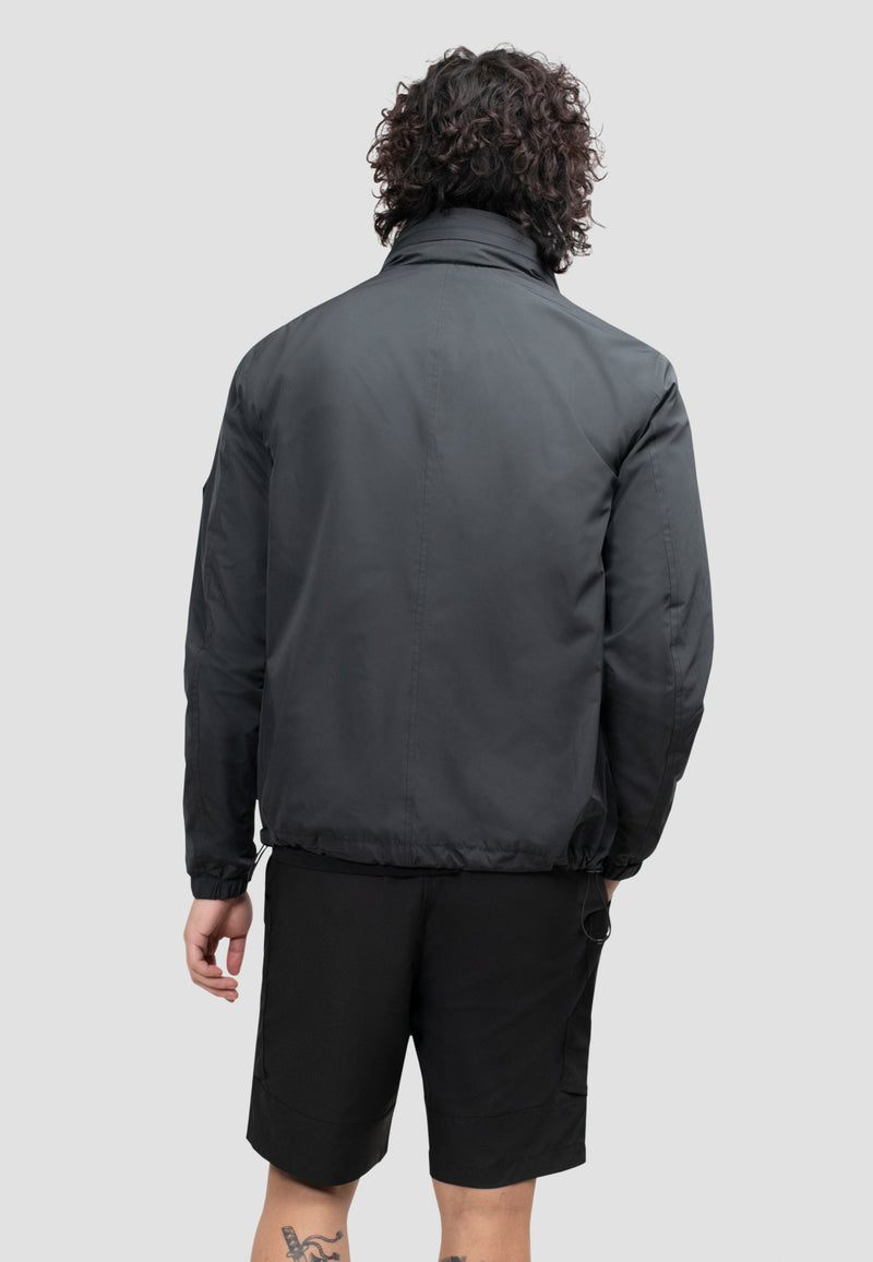 Back view of a model wearing a men's black windbreaker, showcasing its lightweight and functional design.