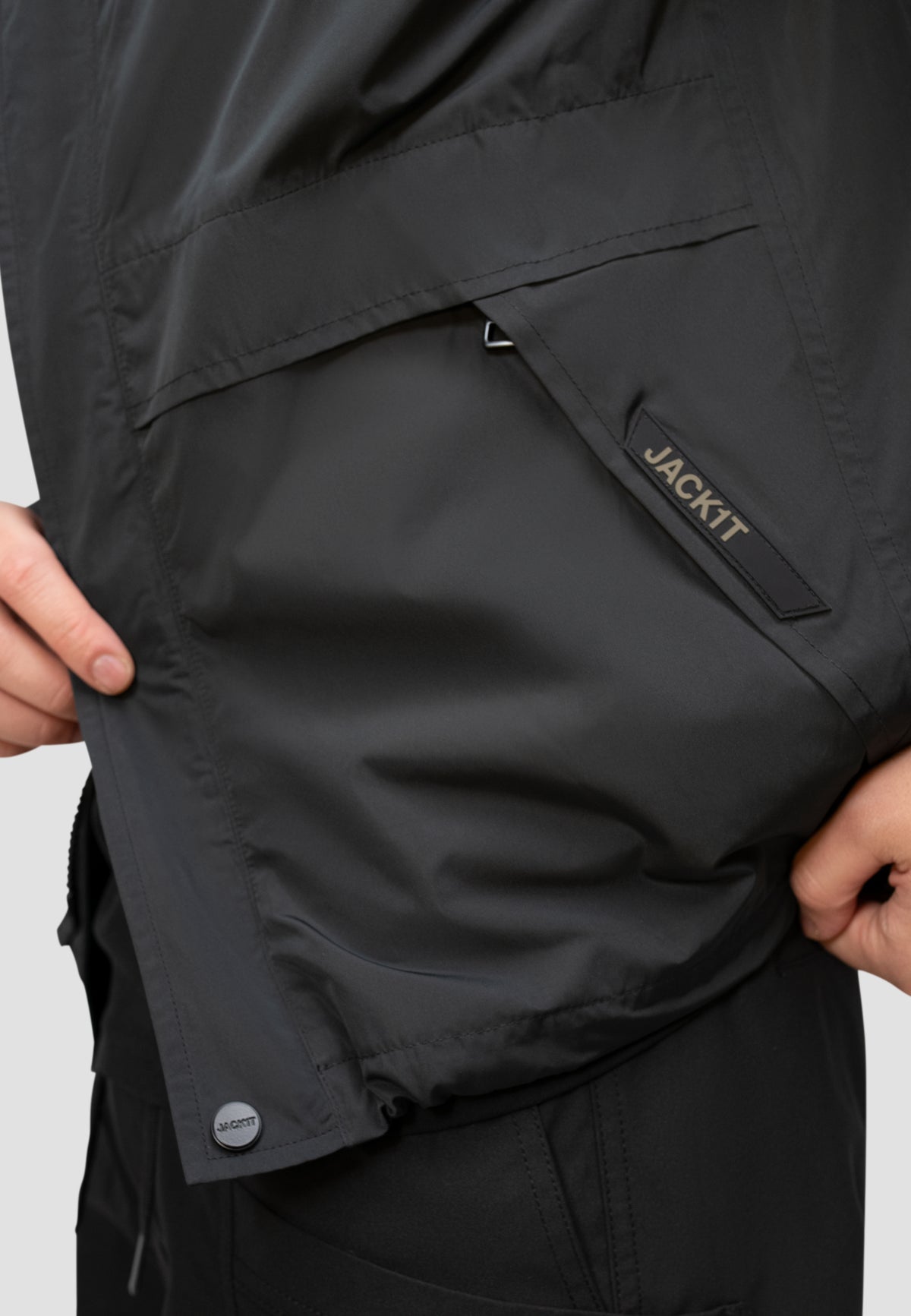 Close-up of the pocket on a men's black windbreaker featuring JACKIT branding.