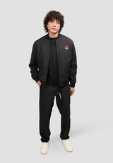 Mens black bomber jacket worn by a model with curly hair, styled with a black t-shirt and black pants.