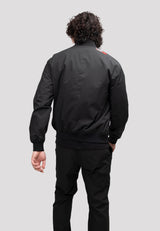 Back view of a man wearing a lightweight mens black bomber jacket with a knit ribbed hem.