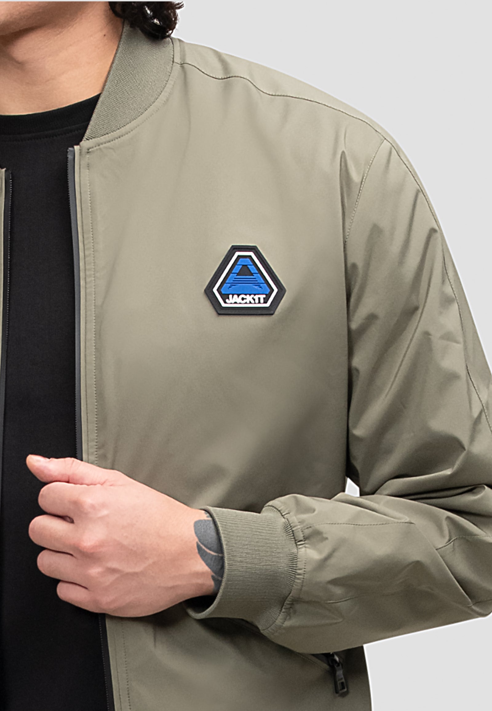 Man wearing a mens olive bomber jacket with logo patch, showcasing lightweight and stylish design.