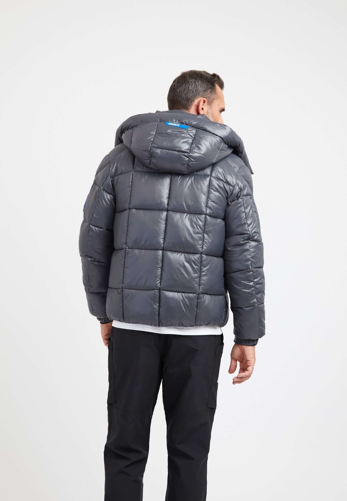 Back view of a man wearing a mens grey racer jacket, featuring a hood and puffer design in graphite black.