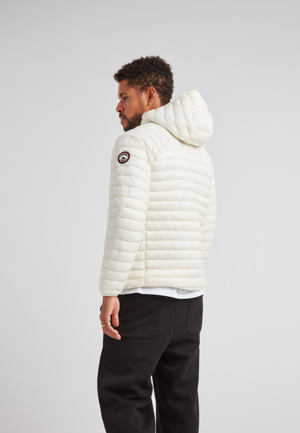 Back view of a man wearing the SATEL1TE Hooded Jacket 2.0 in white, showcasing its stylish and compact design.