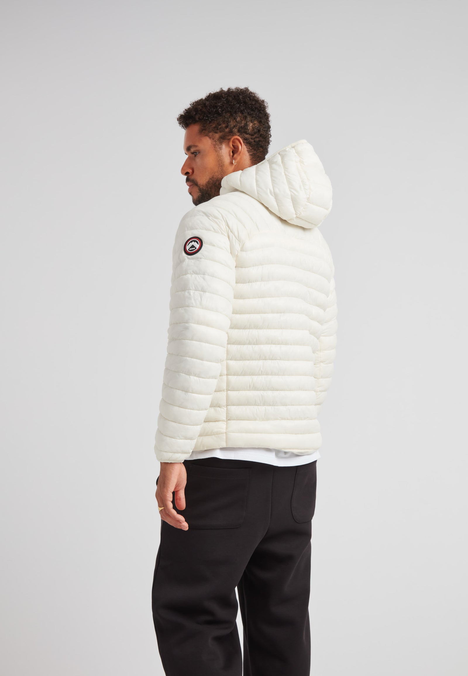 Back view of a man wearing the SATEL1TE Hooded Jacket 2.0 in white, showcasing its stylish and compact design.