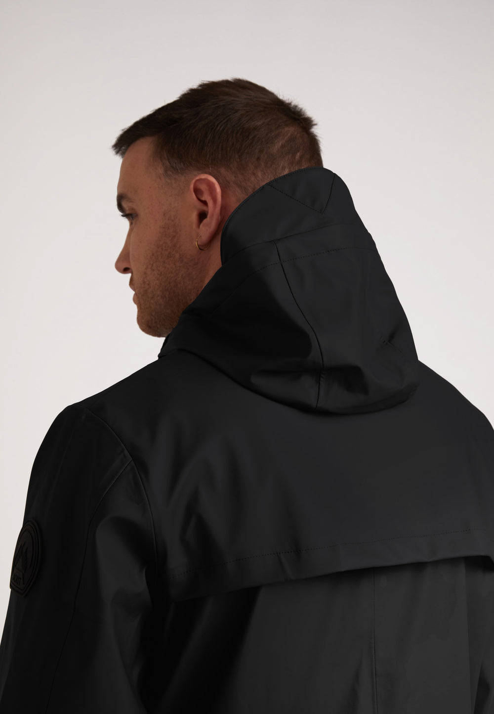 Back view of a model wearing the ELEMENTS Unisex Raincoat 2.0 Black highlighting its sleek hood design.