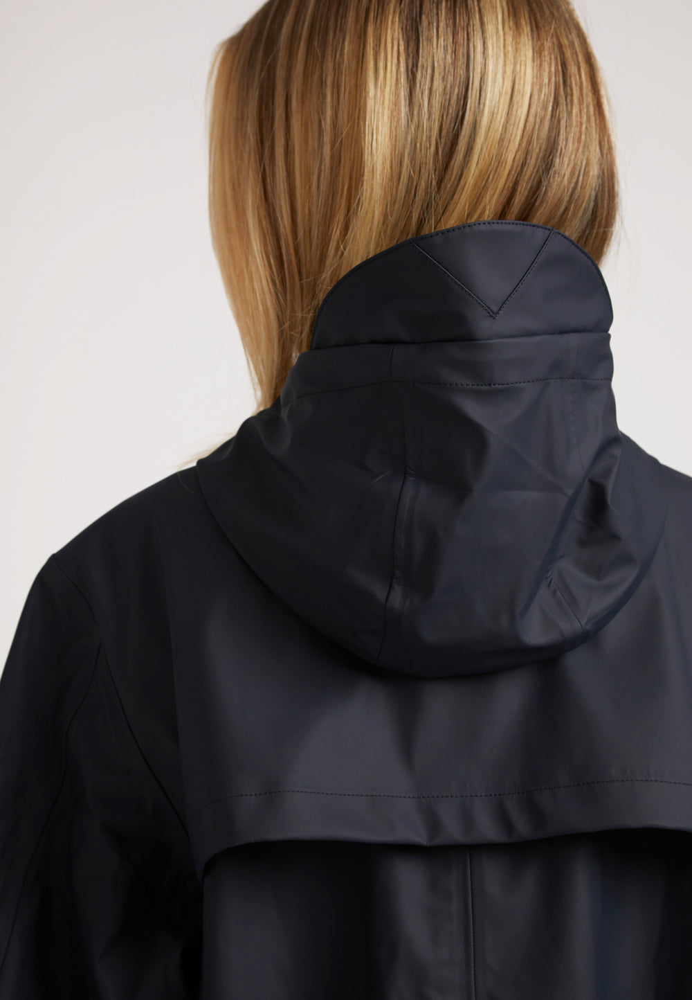 Back view of a woman wearing the ELEMENTS Raincoat 2.0 Navy featuring a hood.