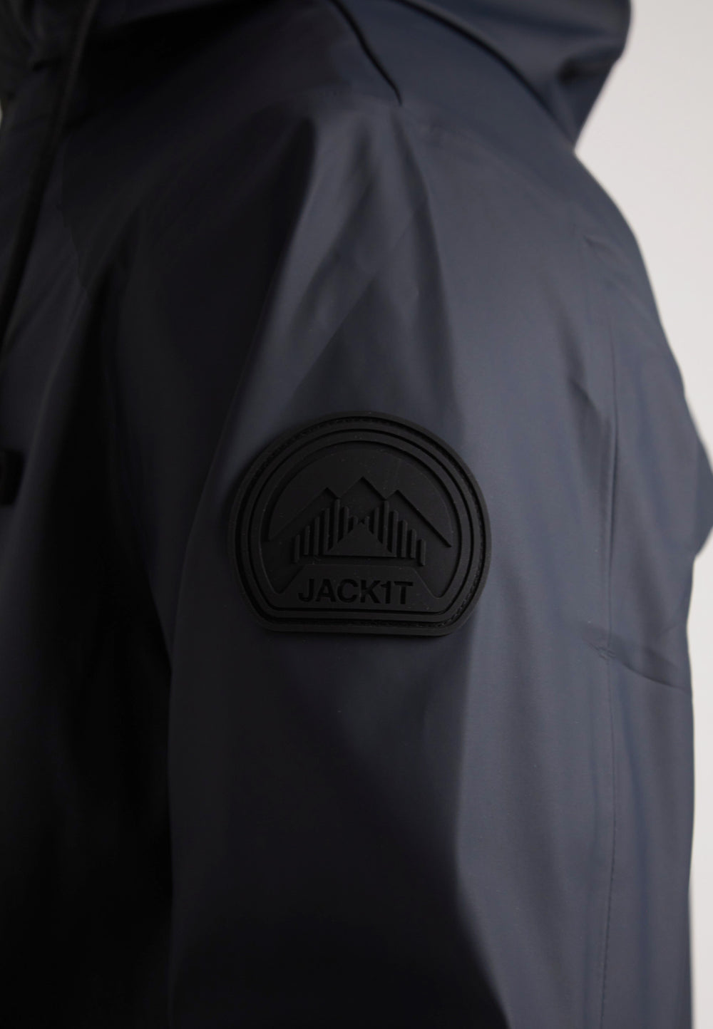 Close-up of JACK1T logo patch on the ELEMENTS Unisex Raincoat 2.0 Navy's sleeve.