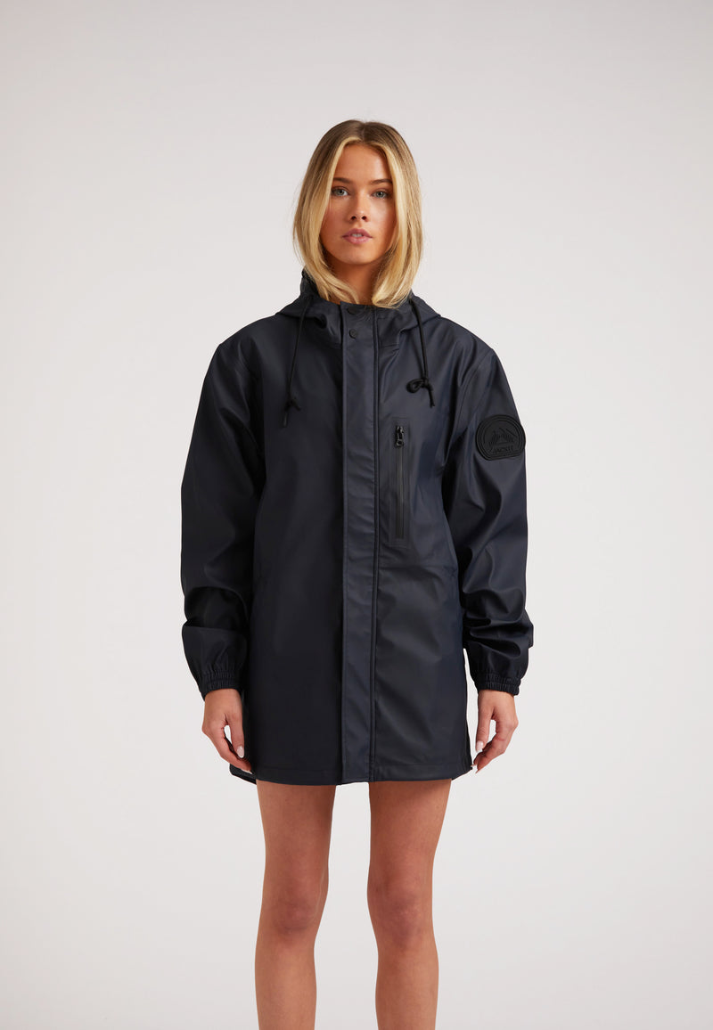 Woman wearing ELEMENTS Raincoat 2.0 Navy, a lightweight waterproof jacket designed for comfort and breathability.