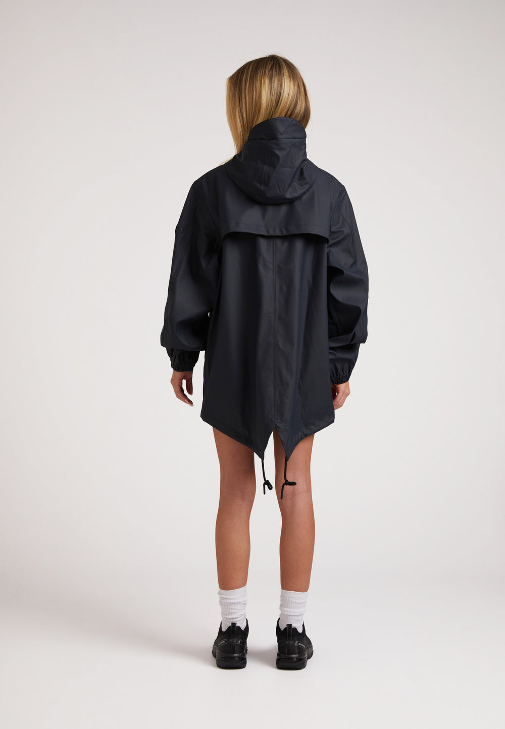 Back view of a model wearing ELEMENTS Raincoat 2.0 Navy, featuring a hood and adjustable hem.