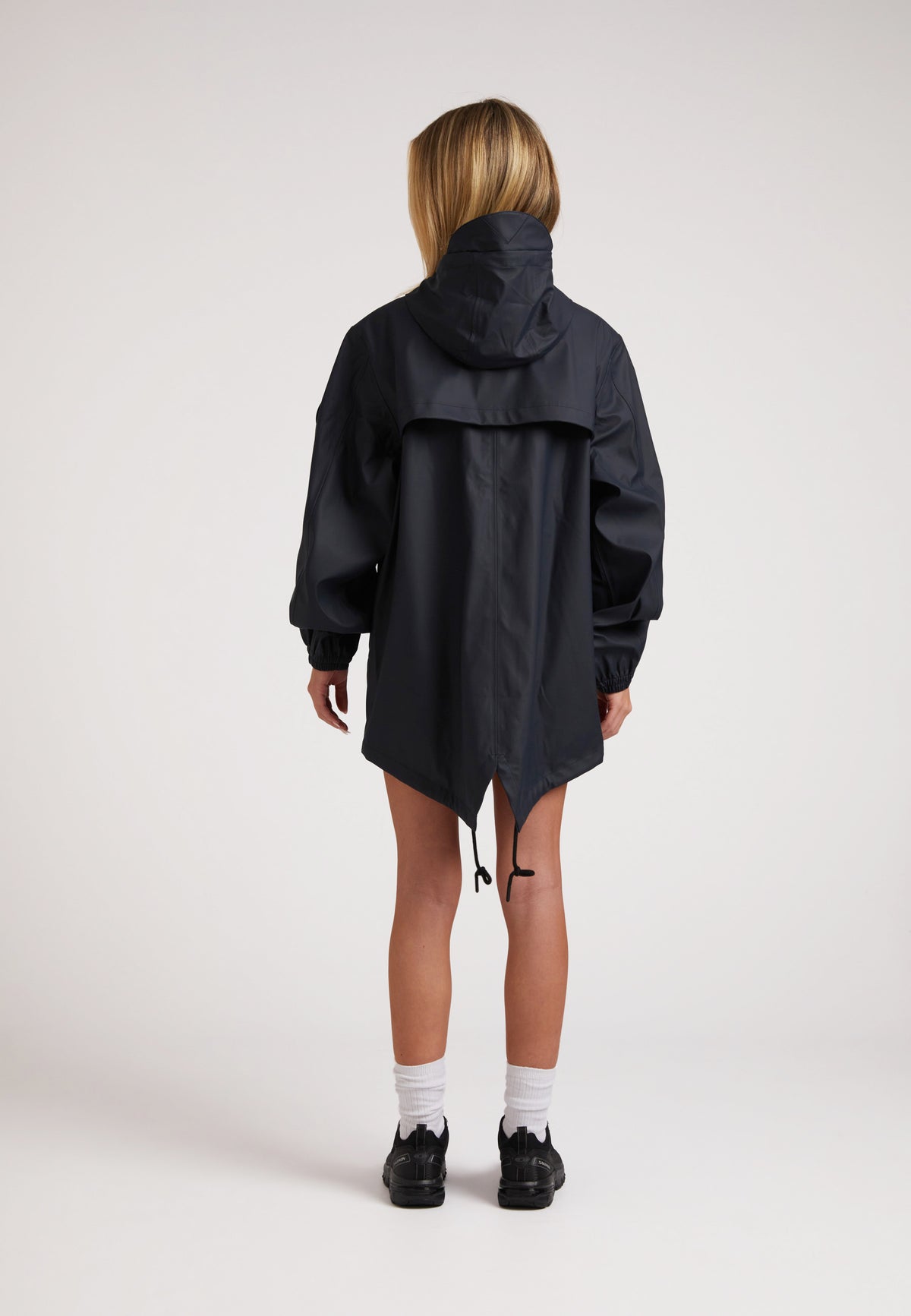 Back view of a model wearing ELEMENTS Raincoat 2.0 Navy, featuring a hood and adjustable hem.