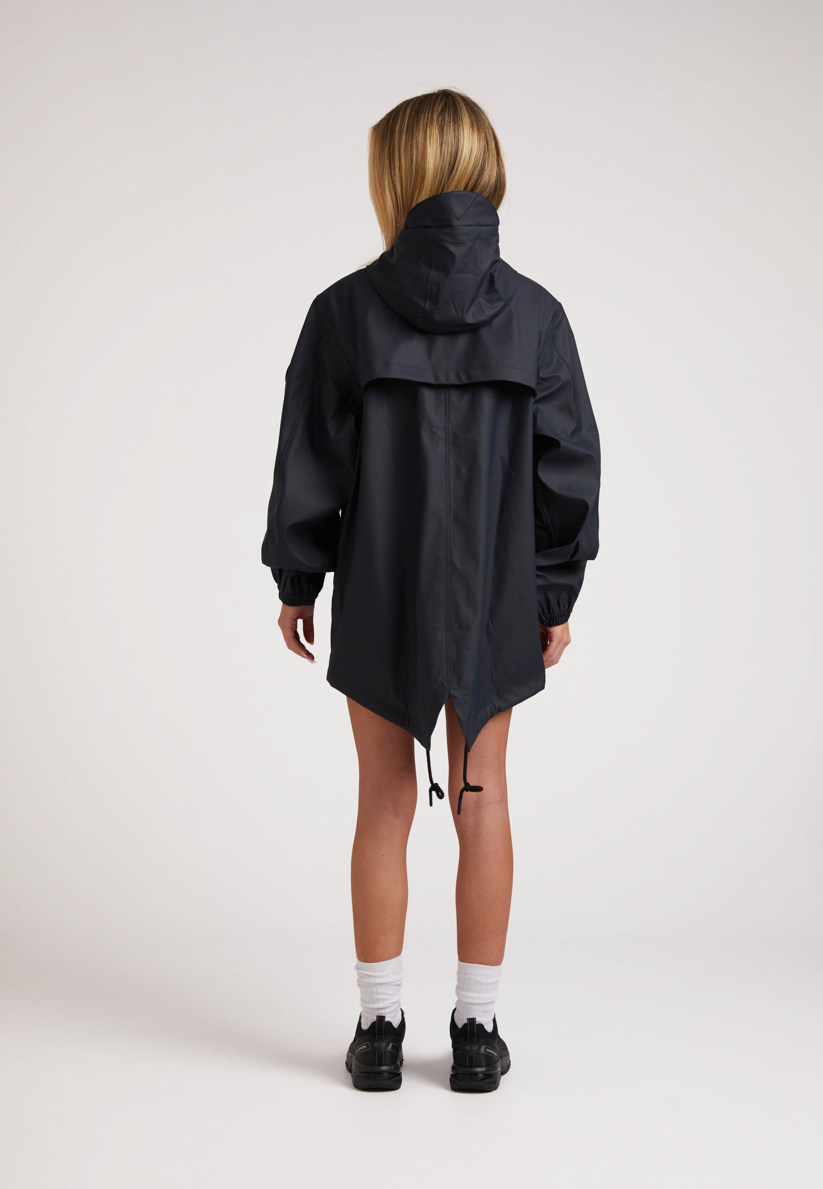 Back view of a model wearing ELEMENTS Raincoat 2.0 Navy, featuring a hood and adjustable hem.