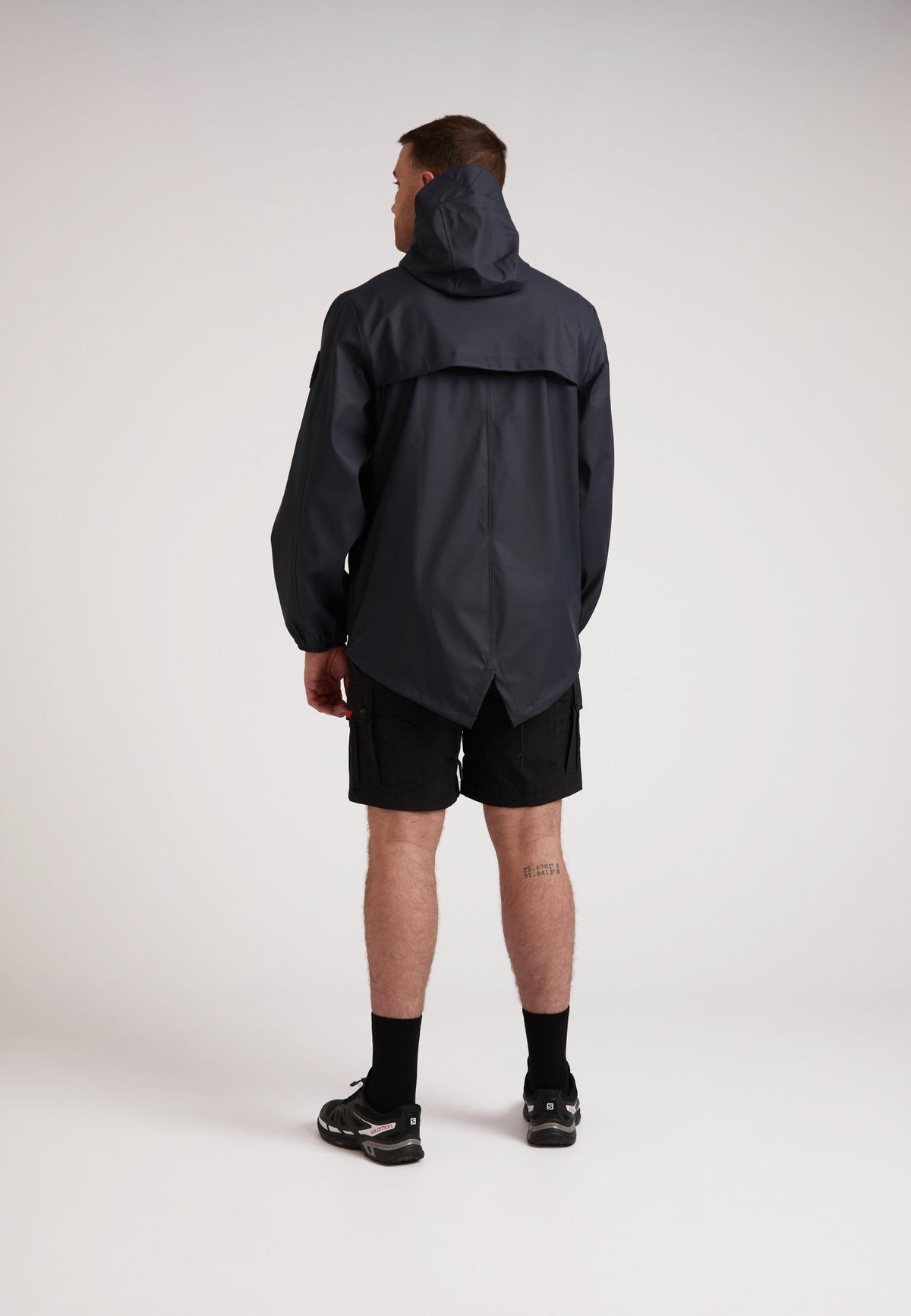 Man wearing ELEMENTS Unisex Raincoat 2.0 Navy seen from the back, showcasing its lightweight and stylish design.