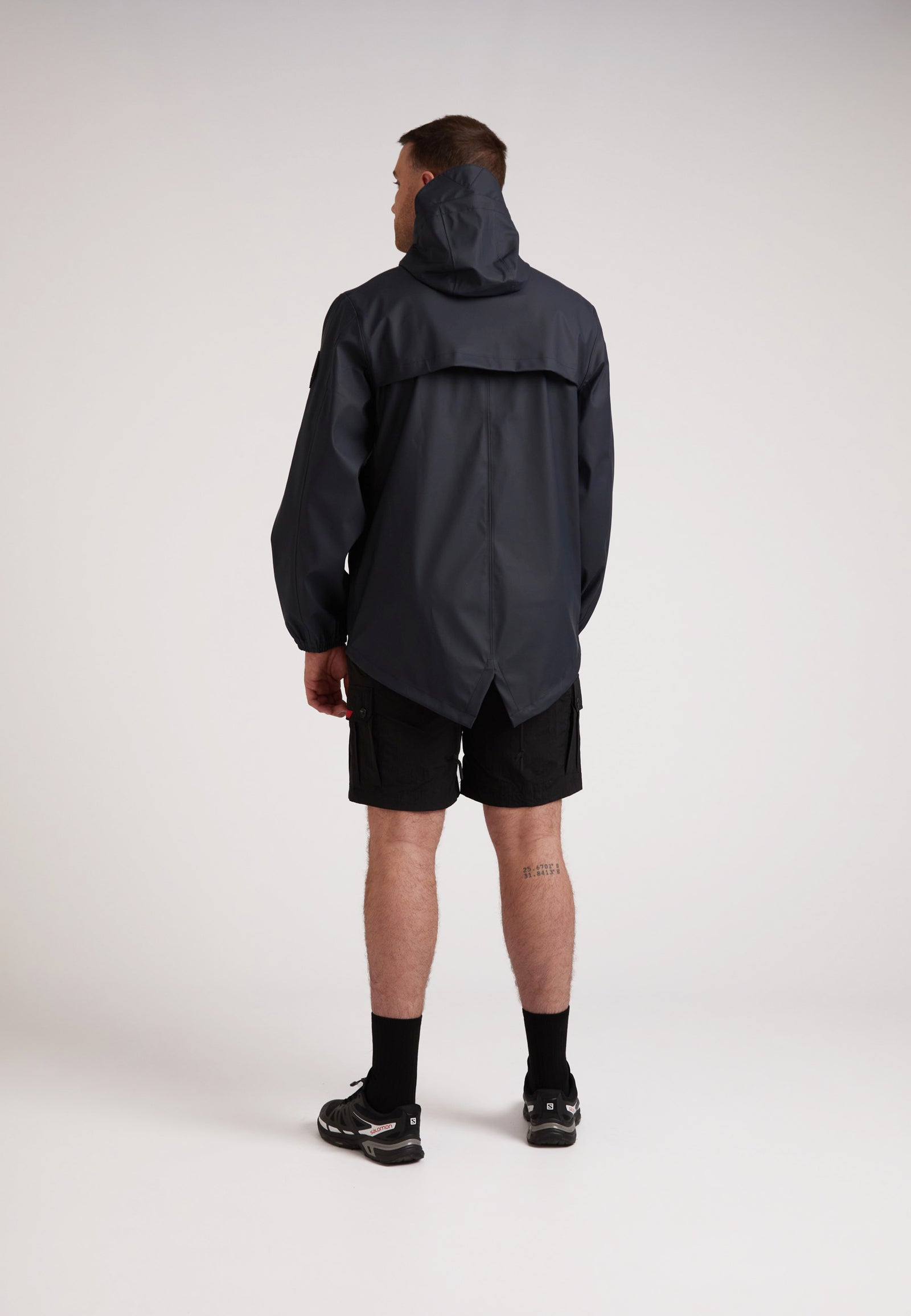 Man wearing ELEMENTS Unisex Raincoat 2.0 Navy seen from the back, showcasing its lightweight and stylish design.