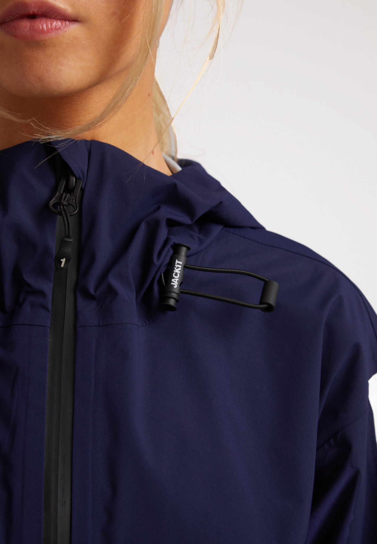 Close-up of a woman wearing an ISOTOPE Ladies waterproof lightweight navy jacket, showcasing the adjustable hood.
