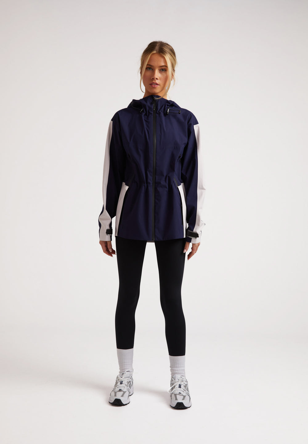 Model wearing ISOTOPE Ladies waterproof lightweight navy jacket with adjustable hood and taped seams.