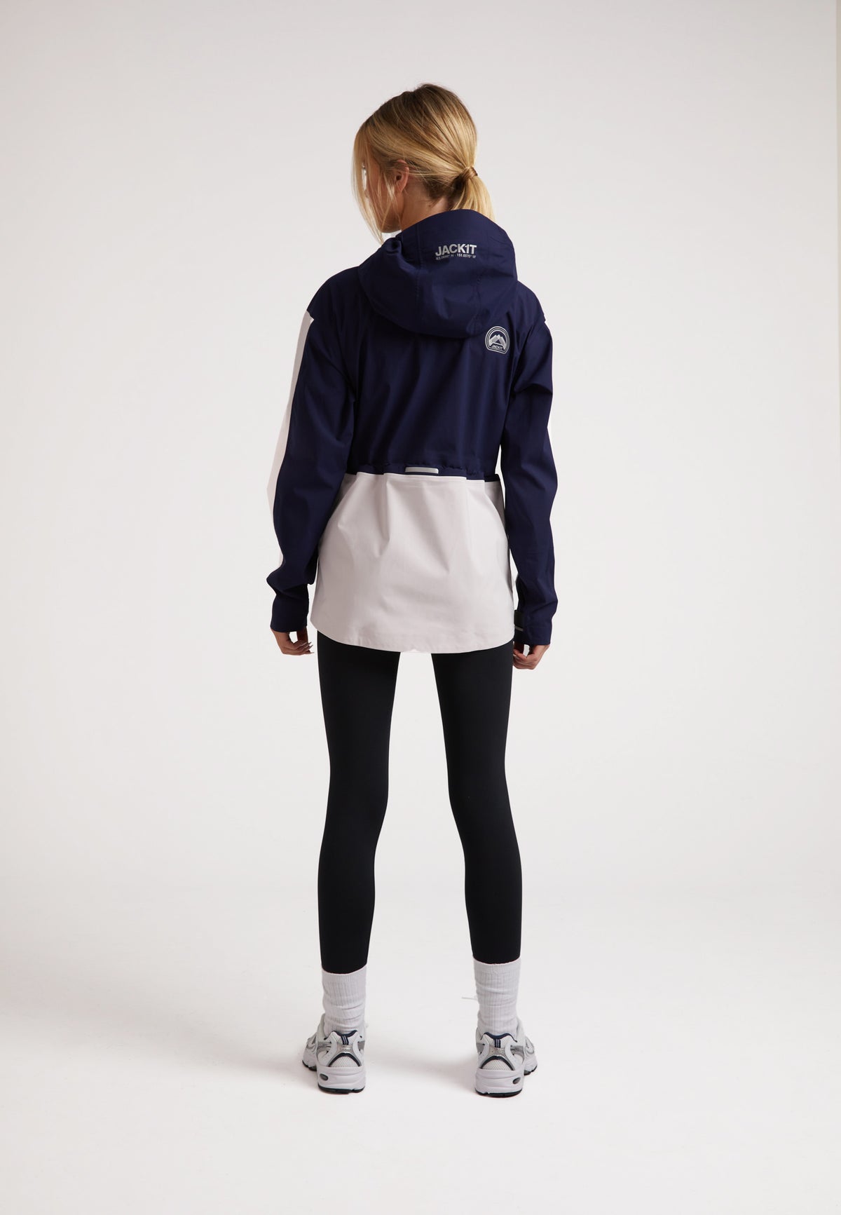 Model wearing a ladies waterproof lightweight navy jacket with adjustable hood and taped seams.