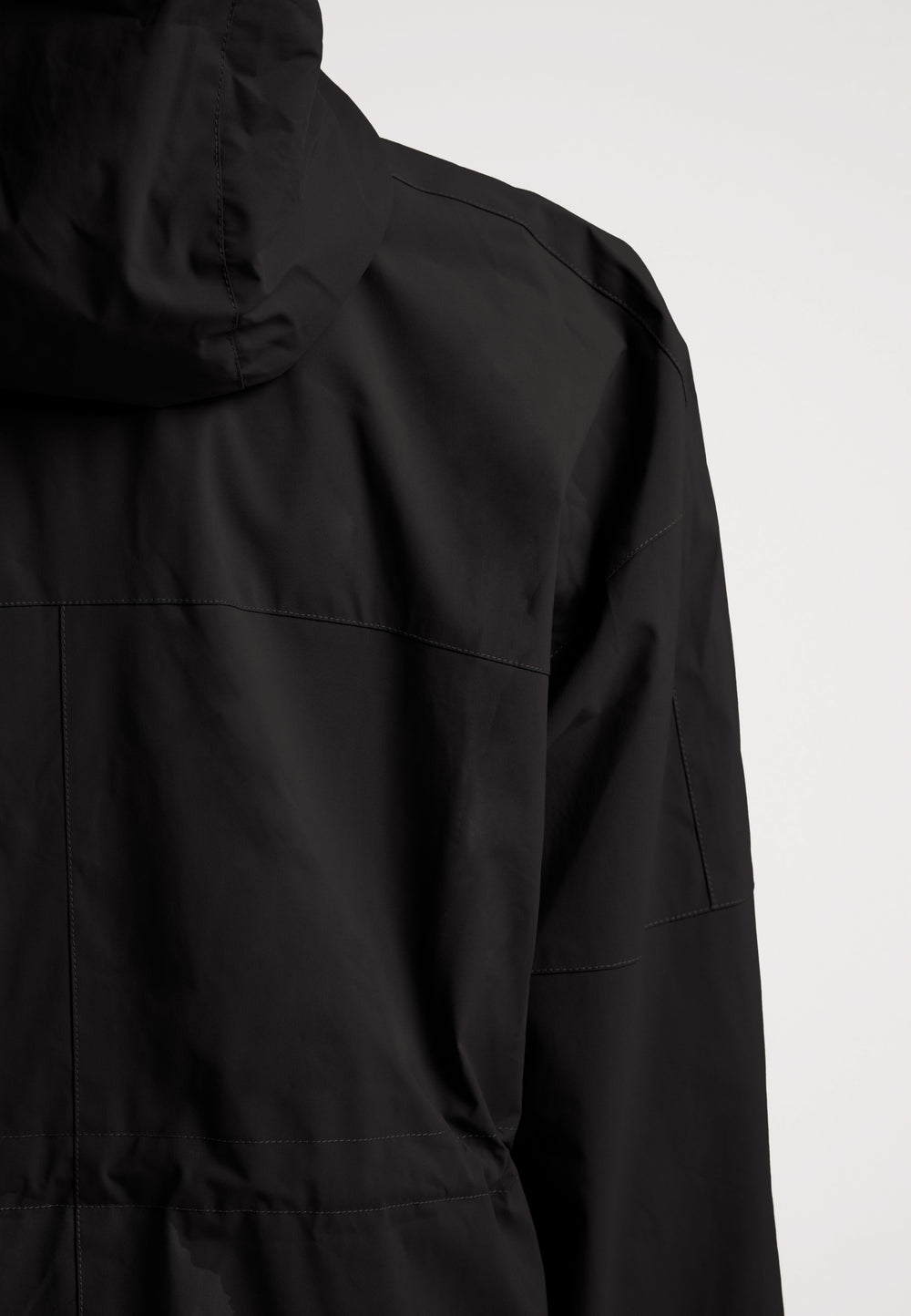 Back view of a ladies lightweight black windbreaker featuring a hood and sleek design.