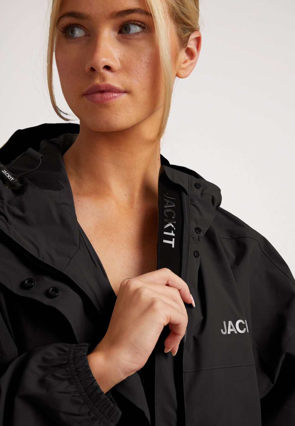 Model wearing ISOTOPE Ladies lightweight black windbreaker with DWR and windproof features.