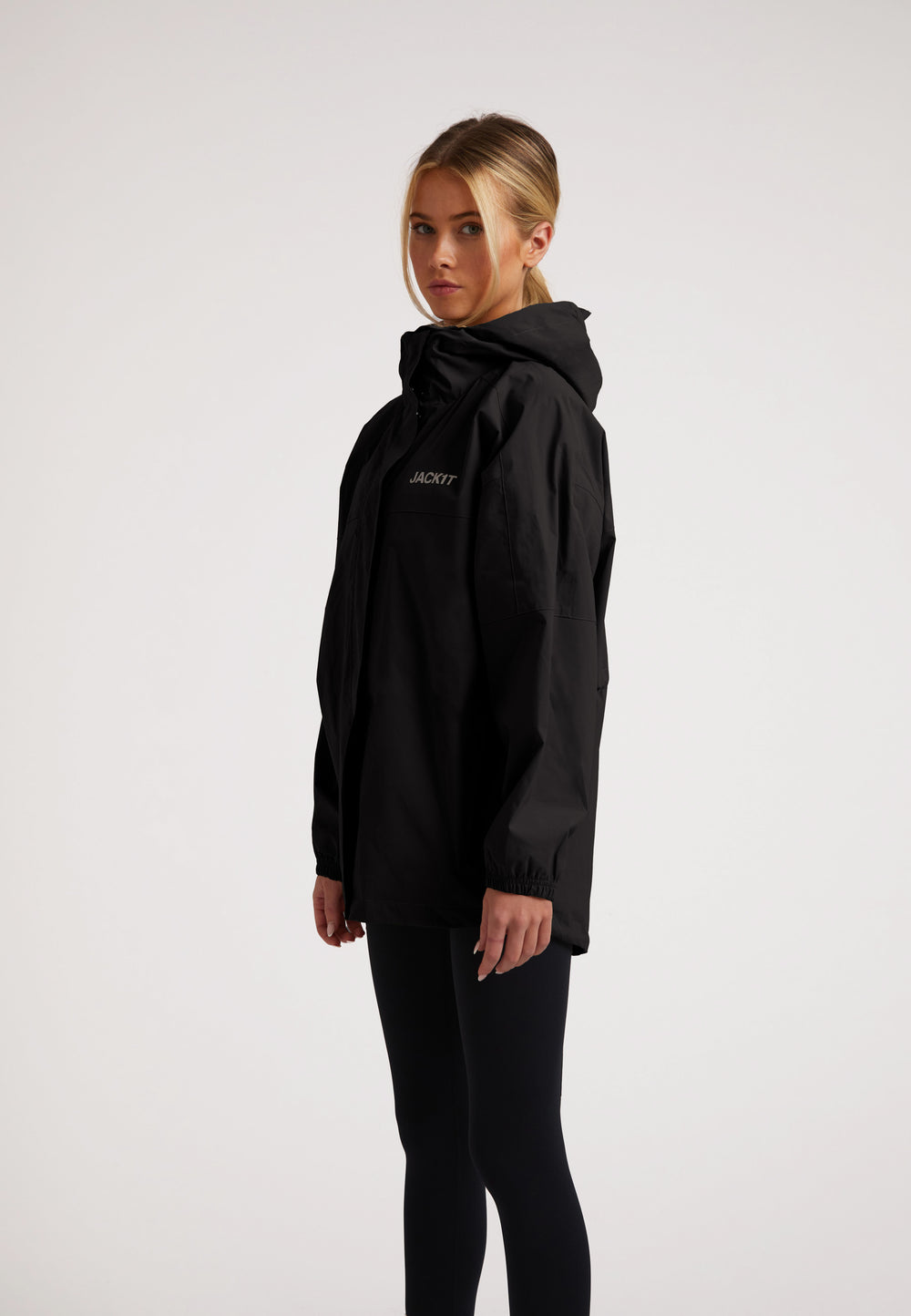 Model wearing ISOTOPE Ladies lightweight black windbreaker, featuring a hood and reflective elements.