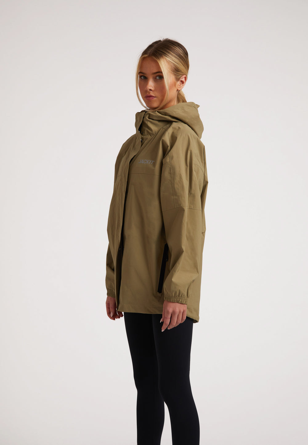Side view of a model wearing a ladies lightweight olive windbreaker with hood, showcasing its stylish design.