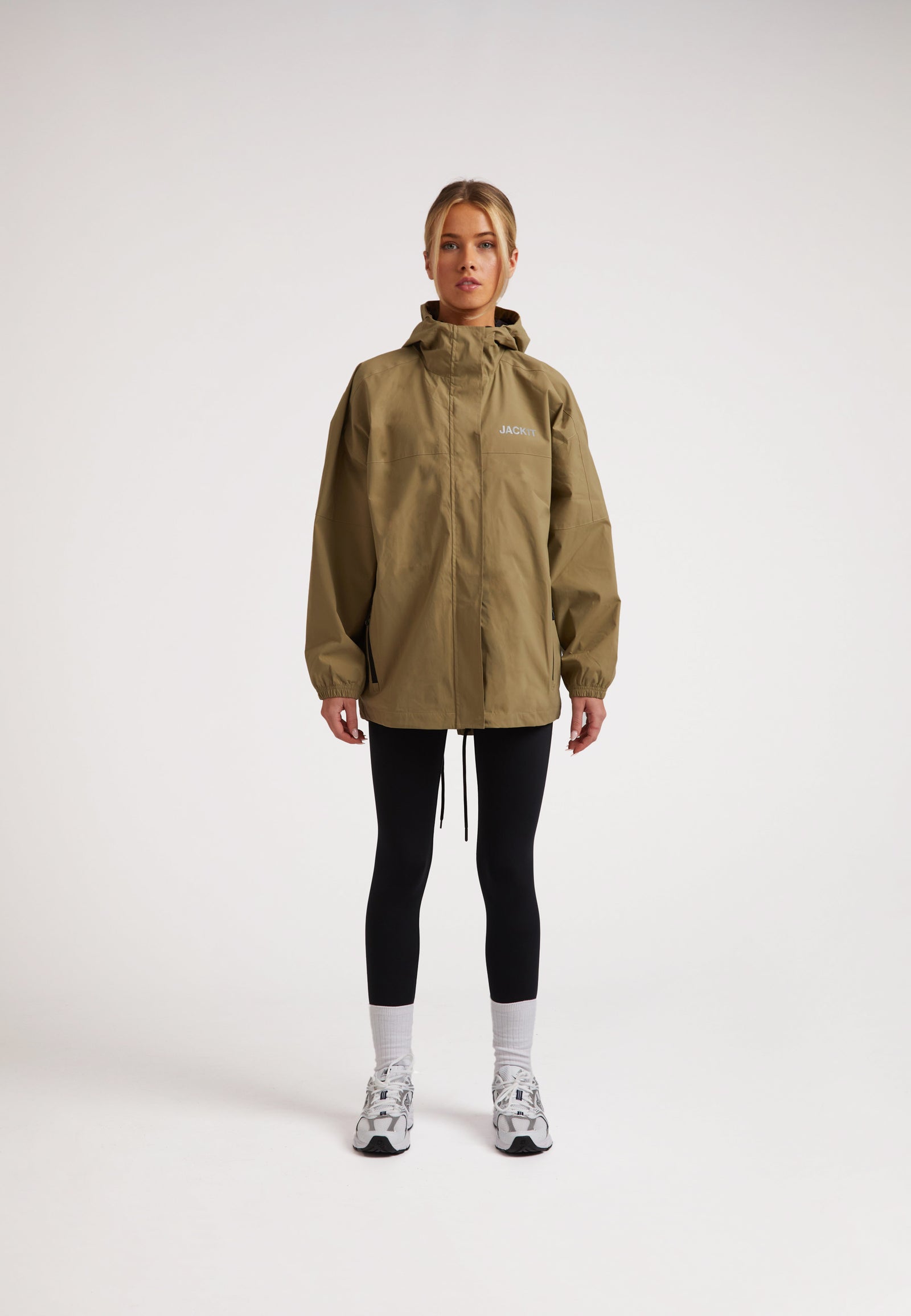 Model wearing ISOTOPE Ladies lightweight olive windbreaker with a hood and reflective elements.