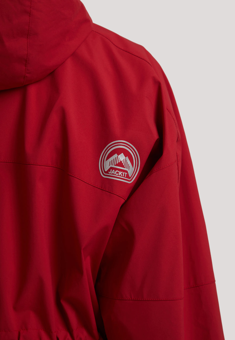 Close-up of the back of a ladies red lightweight windbreaker showcasing the JACKIT logo and hood detail.