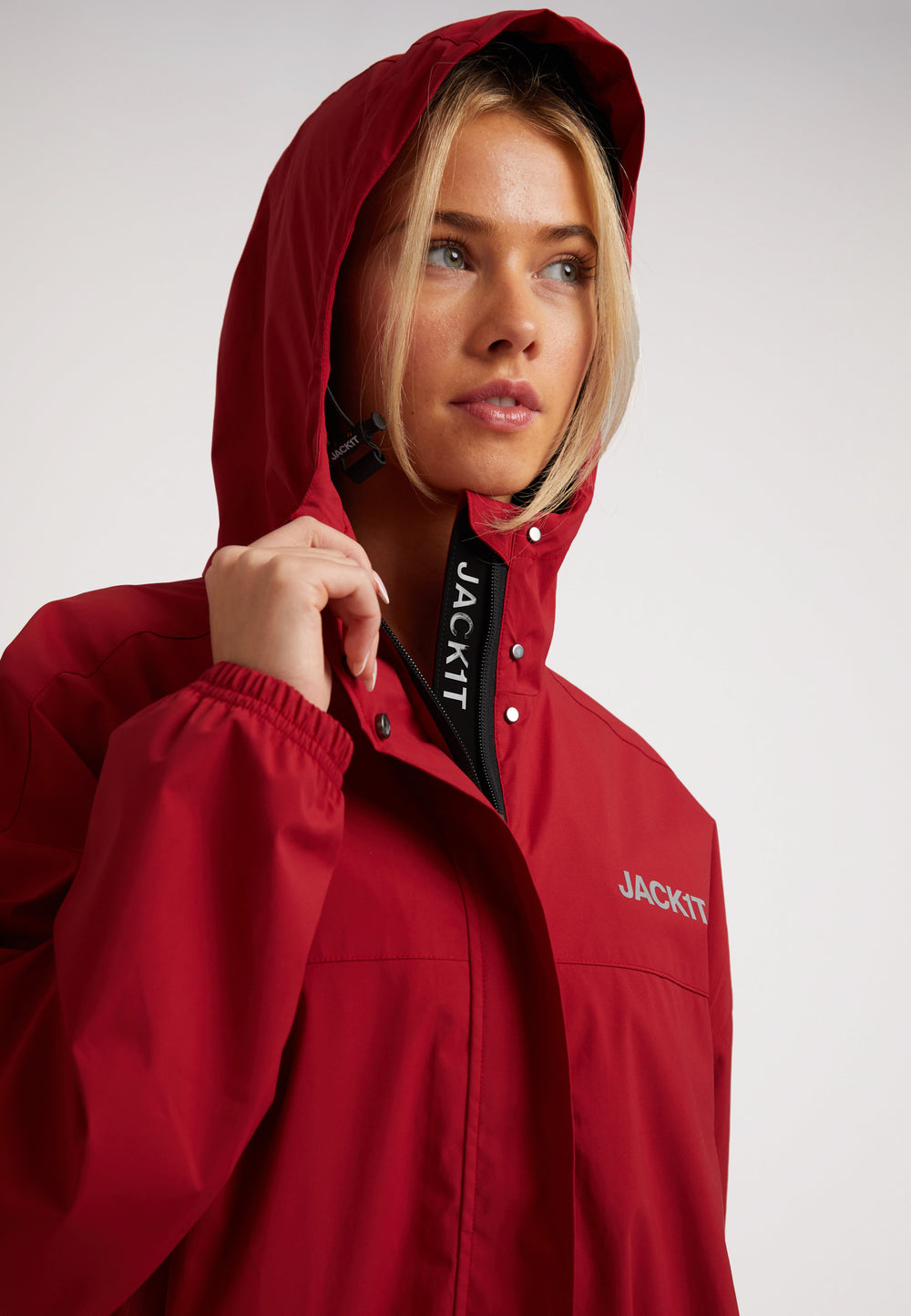 Ladies red lightweight windbreaker featuring a hood and front zipper detail.
