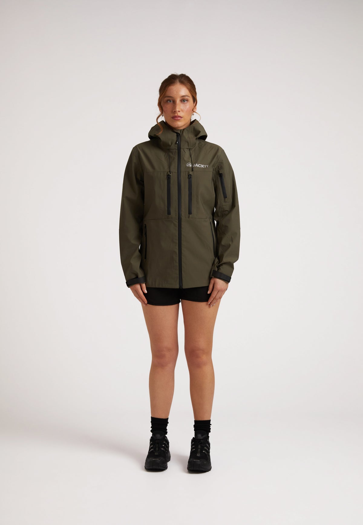 Waterproof ladies jacket in olive, showcasing a woman in a Lithium Waterproof Jacket with hood and pockets.