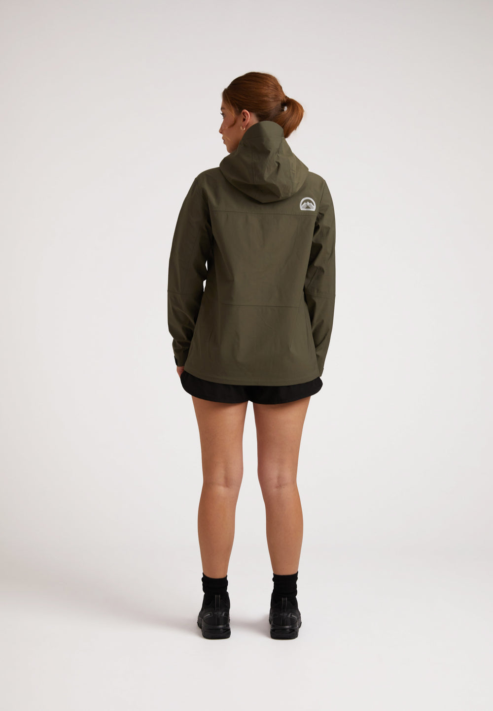 Waterproof ladies jacket in olive worn by a woman, showcasing the back view and hood design.