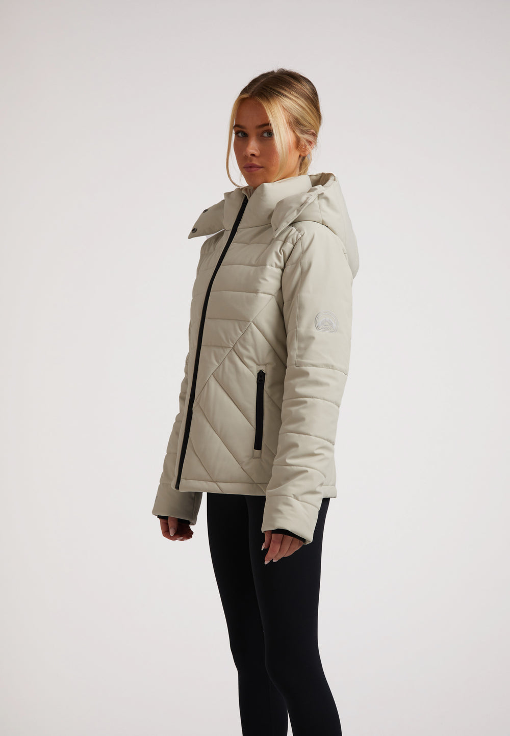 Ladies padded lightweight stone jacket displayed on a model, featuring a hood, side pockets, and stylish design.