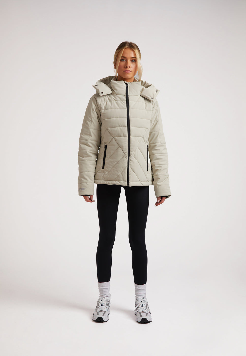 Model wearing ISOTOPE padded jacket, featuring adjustable hood and storm flap, showcasing Ladies padded lightweight stone jacket.
