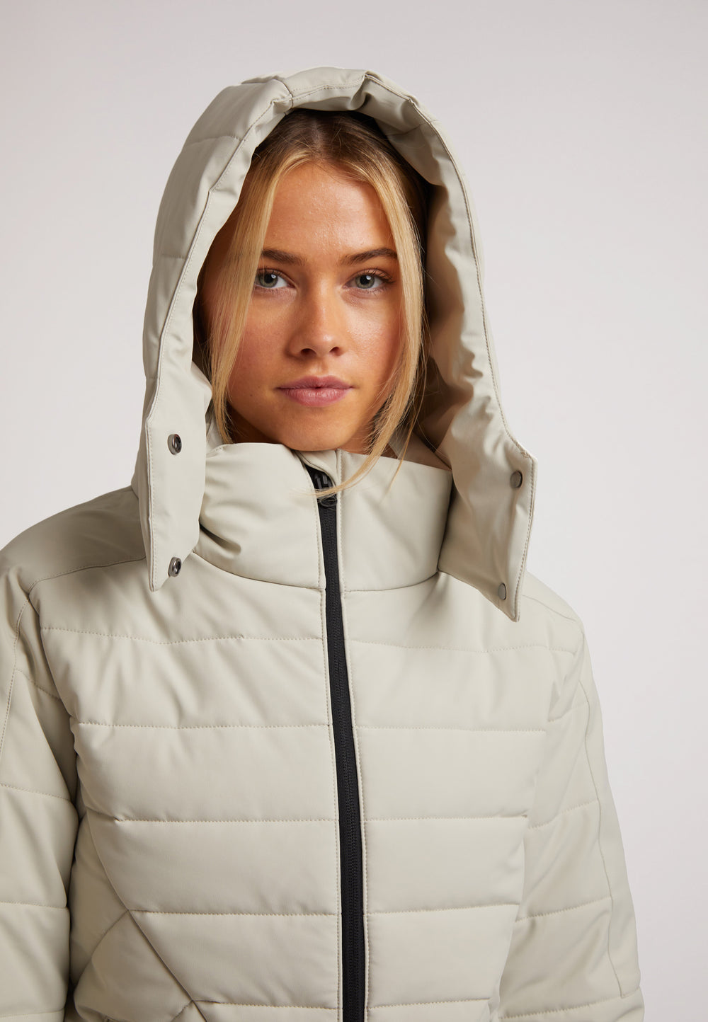 Close-up of a model wearing the ISOTOPE Ladies padded lightweight stone jacket with an adjustable hood.
