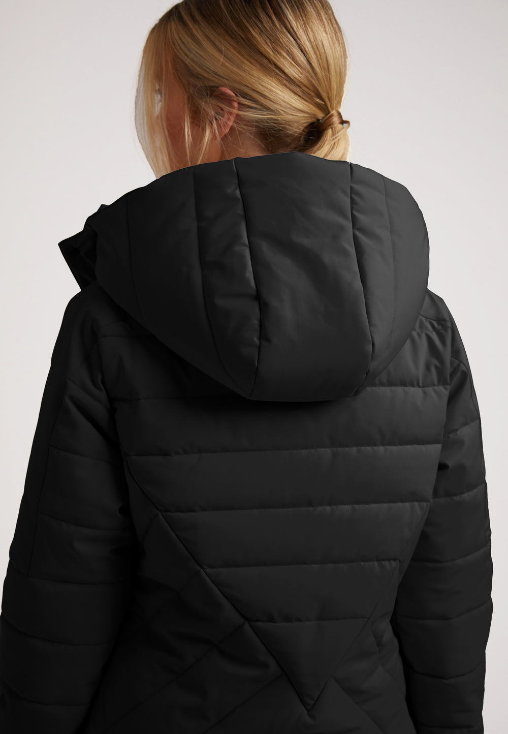 Back view of a woman wearing the ISOTOPE Padded Jacket Black with an adjustable hood.