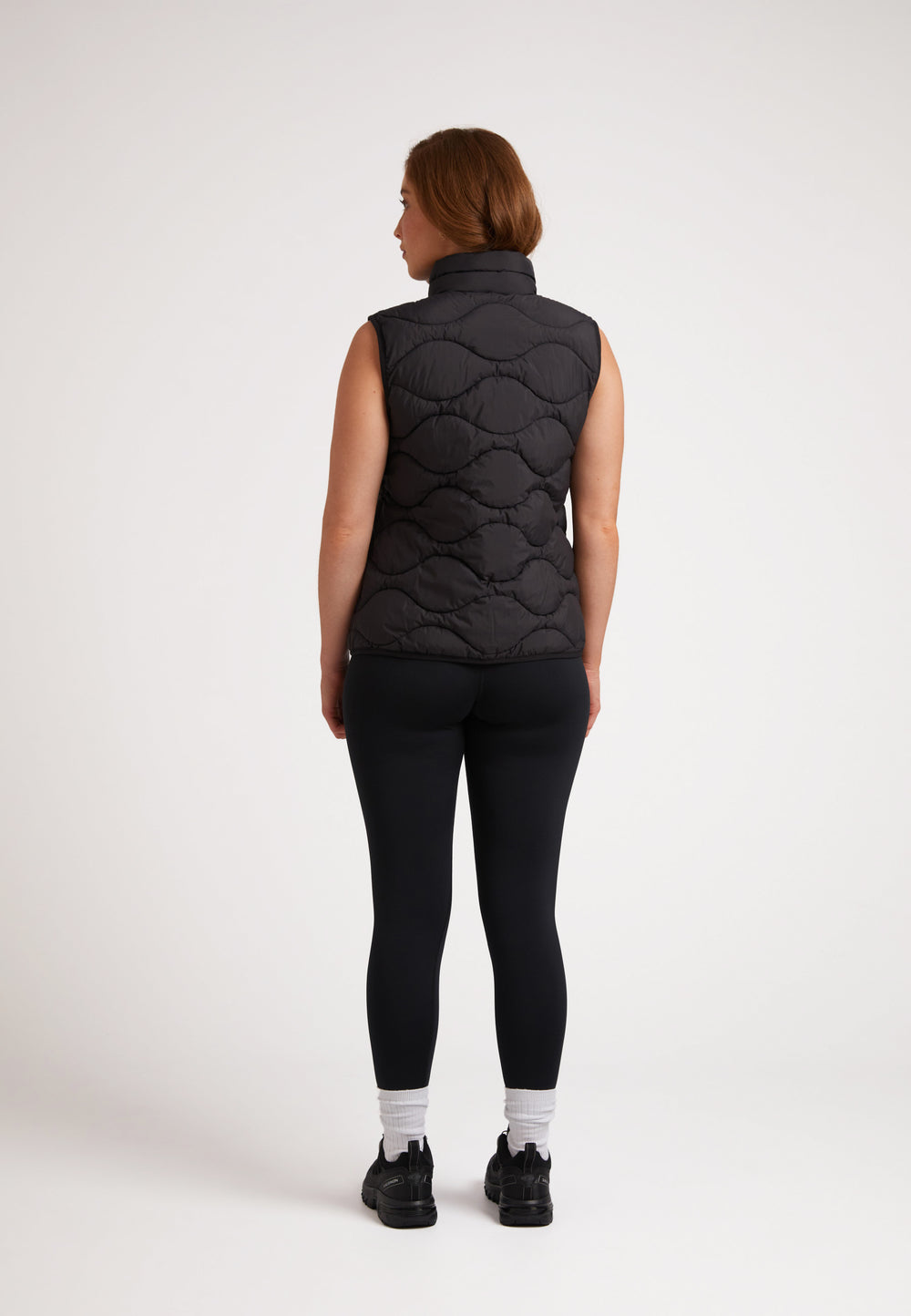 Back view of a model wearing the ORB1T Quilted Gilet Black, showcasing its sleek design and onion baffle construction.