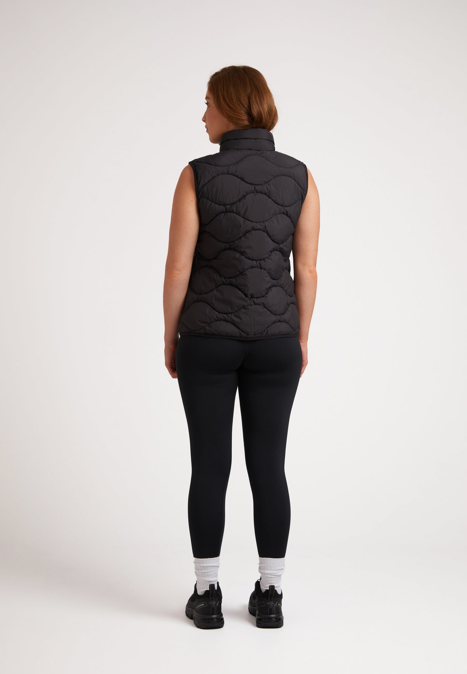 Back view of a model wearing the ORB1T Quilted Gilet Black, showcasing its sleek design and onion baffle construction.